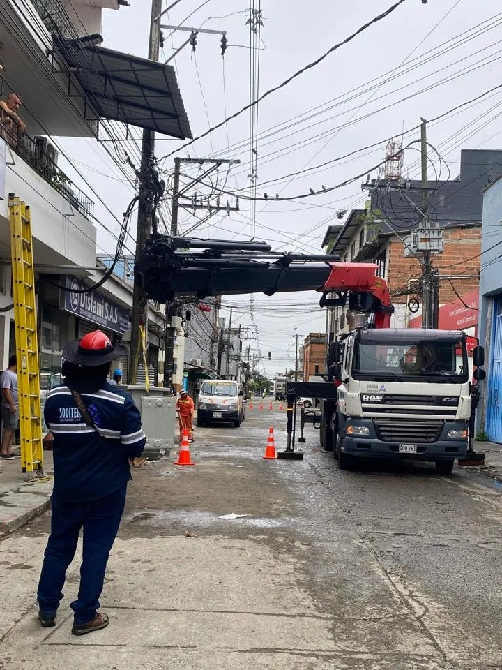 Camión grúa de Soditeel con el brazo extendido junto a un poste de la red, con un técnico de la empresa supervisando desde la calle