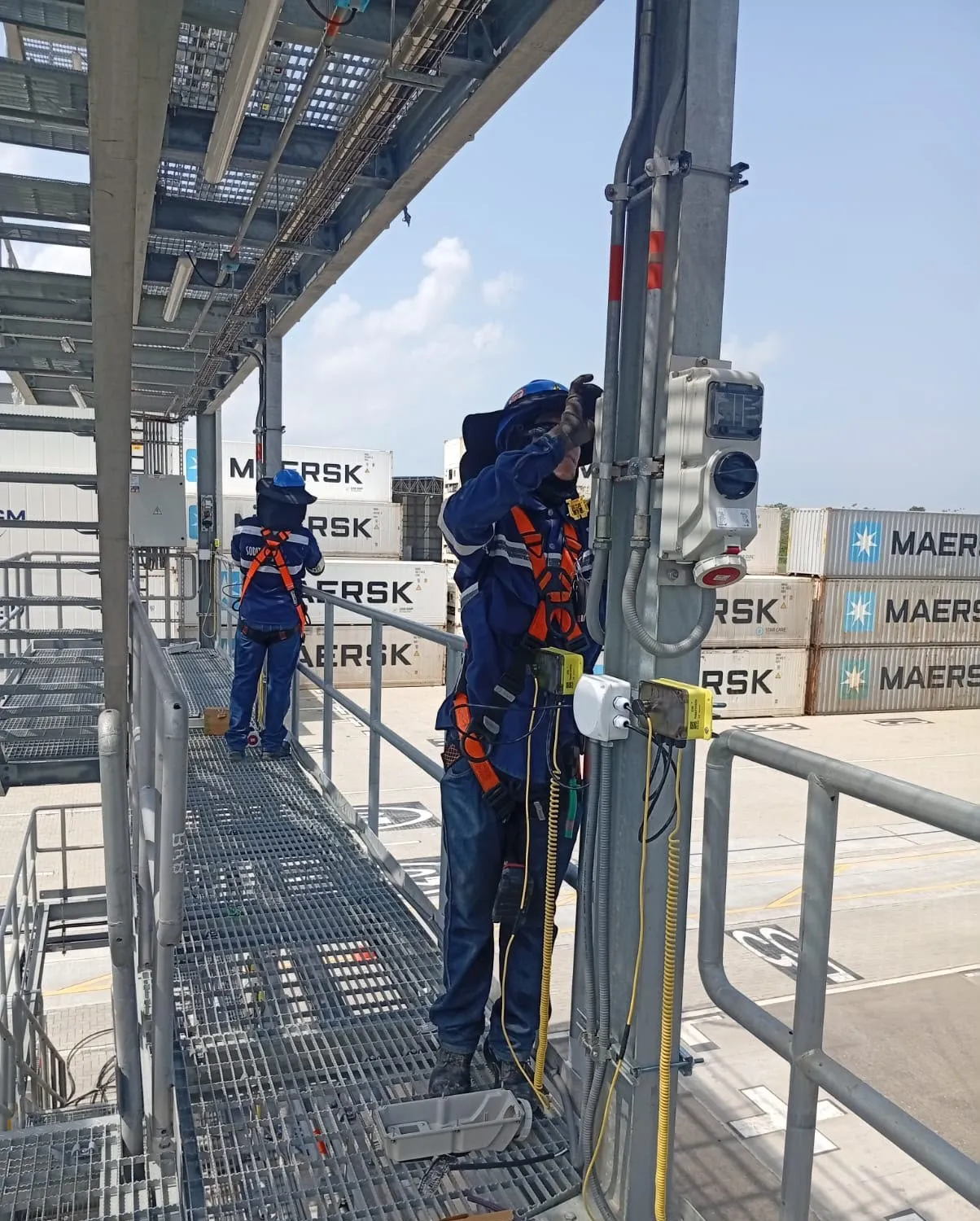 Técnicos de Soditeel con arnés instalando tomas en la plataforma de contenedores refrigerados