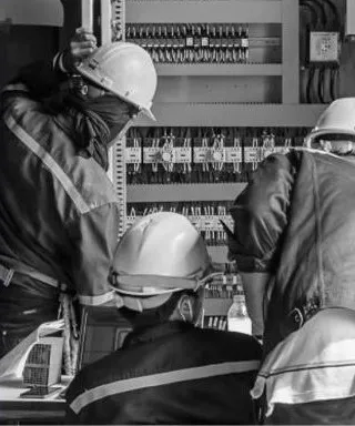Técnicos con casco revisando un tablero de control